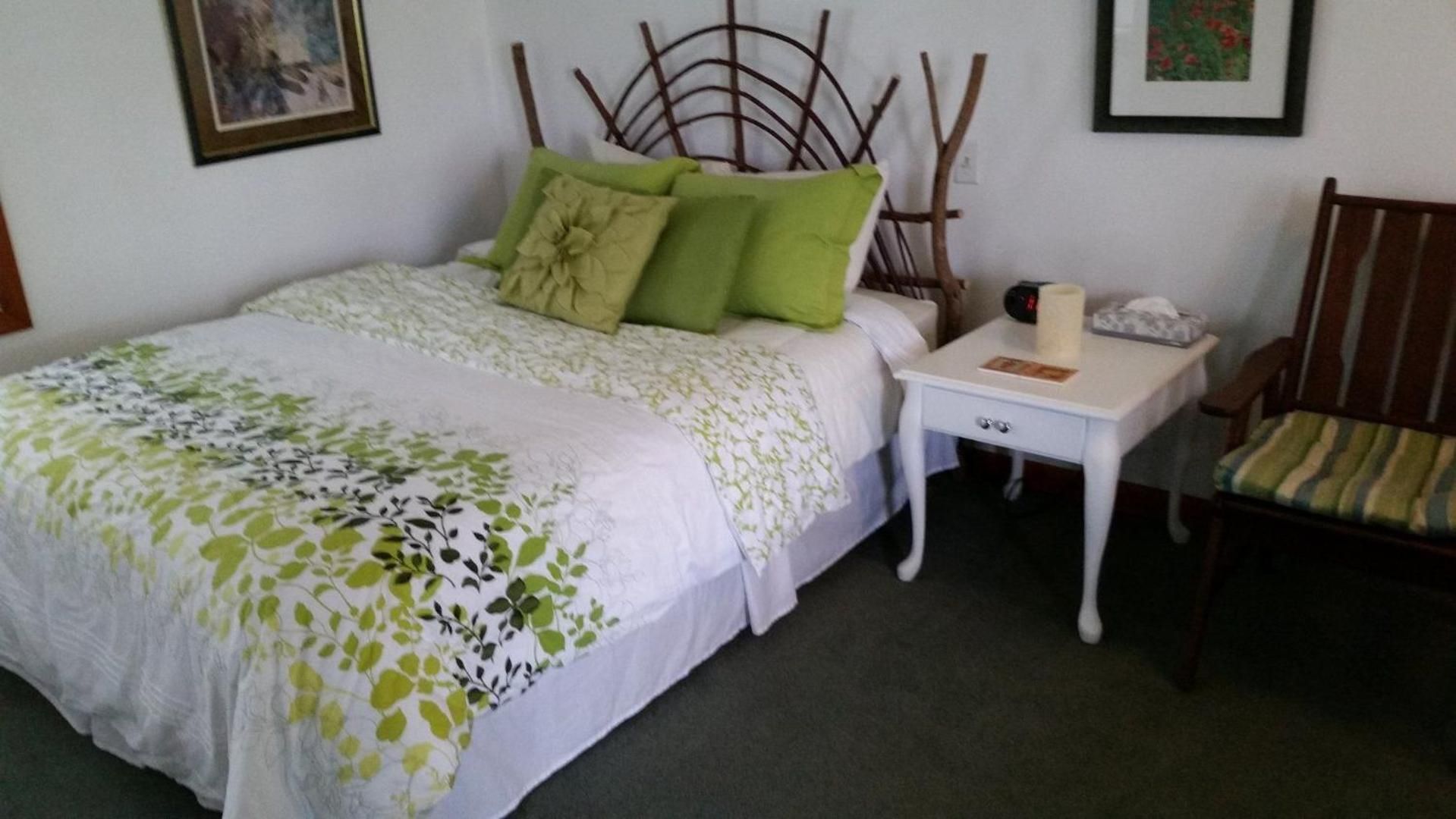 Une chambre à coucher comprenant un lit, une table de chevet, une chaise et une tête de lit fixée au mur.