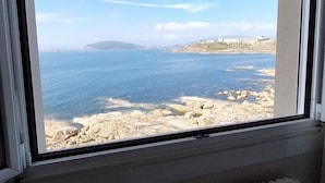 A window with a view of a rocky coastline and the sea. - Hotel Rompeolas (Baiona)