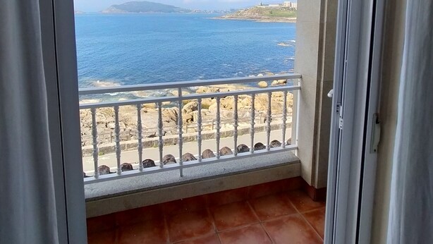 A balcony with a view of the sea and rocky coastline. - Hotel Rompeolas (Baiona)