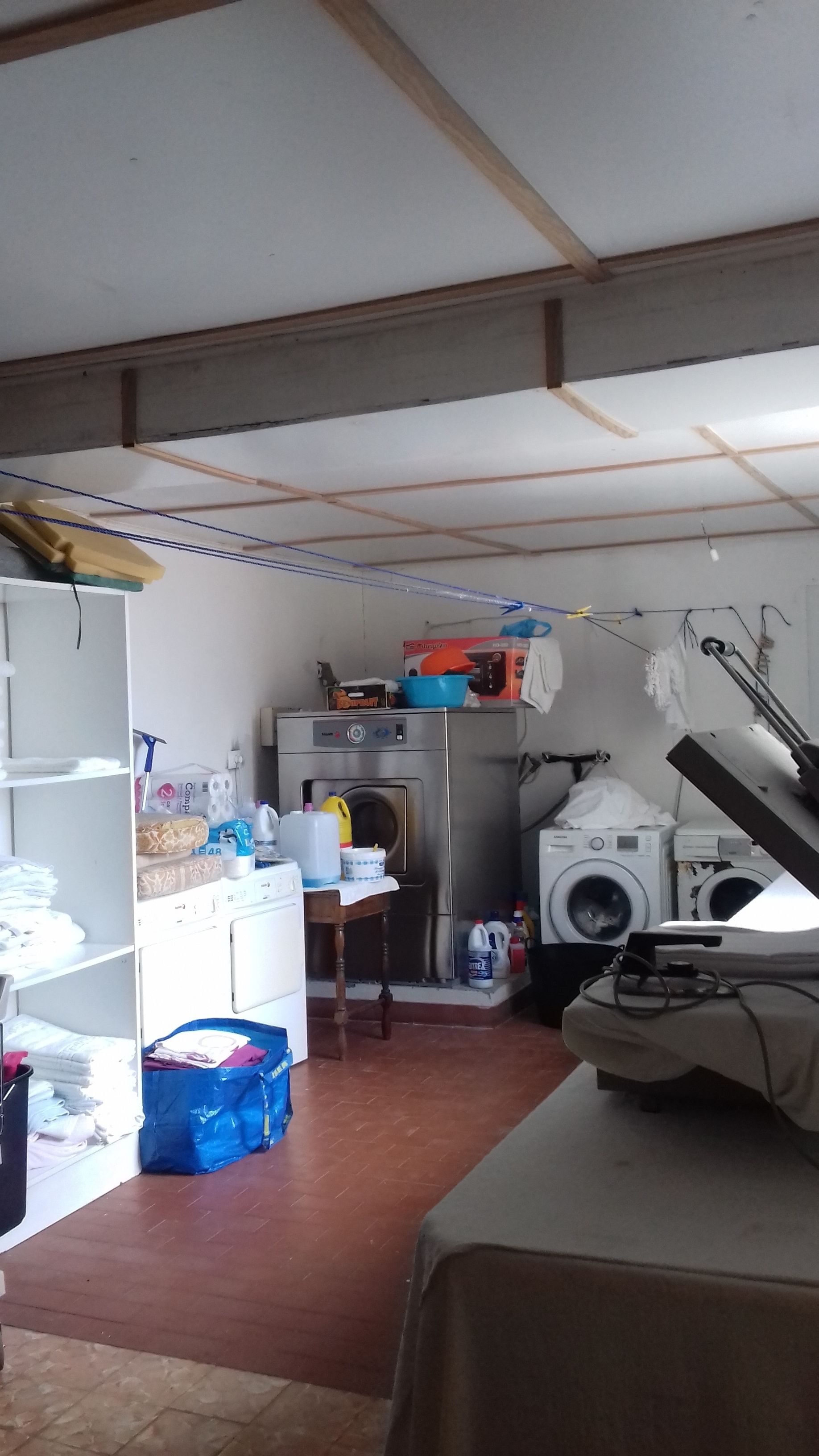 Un lavadero con lavadora, secadora y estantes con ropa doblada.