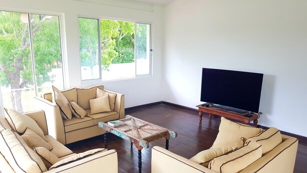 A living room with a sofa set, a coffee table, and a television. - Barn Villa by DARK (Anuradhapura)