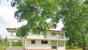 A two-story white building with a balcony, surrounded by lush greenery. - Barn Villa by DARK (Anuradhapura)