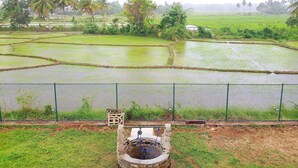 A rural landscape with terraced rice fields, a fence, and a traditional water well. - Barn Villa by DARK (Anuradhapura)