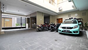 Un parking à plusieurs niveaux où sont garées plusieurs motos et une voiture bleu clair.