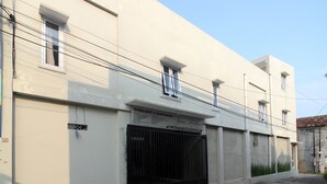 Un bâtiment avec une enseigne indiquant « Terima Kost & Guesthouse » et un portail noir.