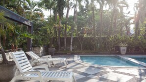 A poolside area with lounge chairs and a tiled deck. - RedDoorz Premium @ Raya Nginden (Surabaya)