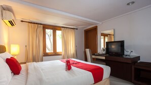 A hotel room with a bed, a desk with a television, and a window with curtains. - RedDoorz Premium @ Raya Nginden (Surabaya)