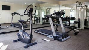 A gym with treadmills, ellipticals, and free weights. - RedDoorz Premium @ Raya Nginden (Surabaya)
