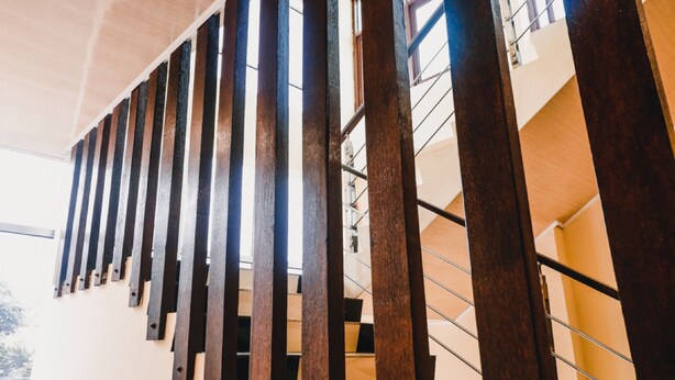 Un escalier avec des rampes en bois et des balustrades en métal, menant à l’étage supérieur.