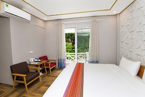 Ein Hotelzimmer mit Bett, Schreibtisch, Stuhl und Blick auf Grünflächen durch das Fenster.