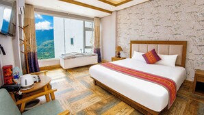 Une chambre d’hôtel avec un grand lit, un bureau avec une chaise, une fenêtre donnant sur un paysage agréable et une salle de bain.