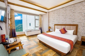 Ein Hotelzimmer mit einem großen Bett, einem Schreibtisch mit Stuhl, einem Fenster mit Ausblick und einem Badezimmer.