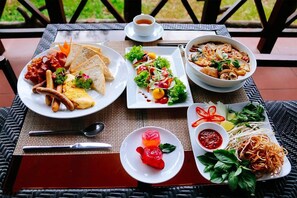 A table with various dishes including a salad, noodles, and a bowl of soup.
