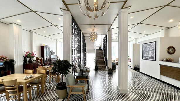 Un hall d’hôtel doté d’un sol à motifs géométriques, d’un escalier et d’un lustre.