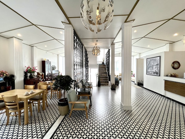 Eine Hotelhalle mit einem geometrisch gemusterten Boden, einer Treppe und einem Chandelier.