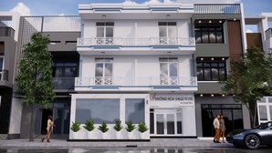 Un hôtel à la façade blanche, doté d’un balcon et d’une enseigne indiquant « Muong Hoa Valley Hotel ».
