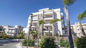 A modern multi-story building with balconies, surrounded by palm trees and other greenery. - La Casa del Cardinale (Monopoli)