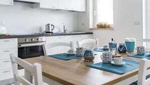 A modern kitchen with white cabinets, a wooden table, and blue and white tea sets. - La Casa del Cardinale (Monopoli)