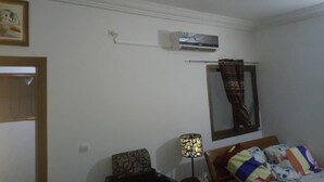 Una stanza con un letto, una lampada, un condizionatore d'aria e una ventola a soffitto.