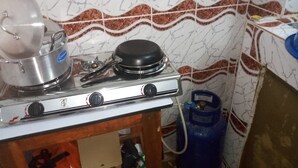 Una cucina con un fornello a gas, una pentola sul bruciatore di sinistra e una bombola a gas blu alla destra.