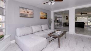 A modern living room with a gray sectional sofa, a glass coffee table, and two paintings on the wall. - Hollywood Castle Palace (Hollywood)