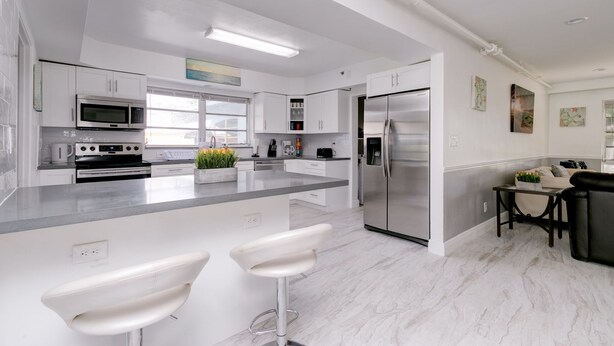 A modern kitchen with white cabinets, stainless steel appliances, and a marble countertop. - Hollywood Castle Palace (Hollywood)