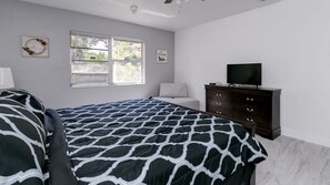 Een slaapkamer met een bed, een dressoir, een televisie en twee decoraties aan de muur.