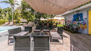 Een terras buiten met rieten meubilair, een zwembad en een muurschildering.