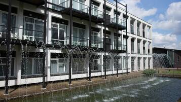 A modern building with multiple balconies and a water feature in front.