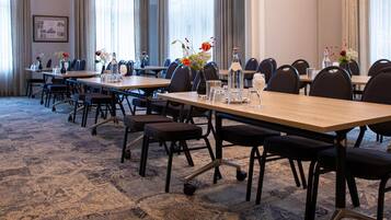 A conference room with multiple tables and chairs, arranged in rows.