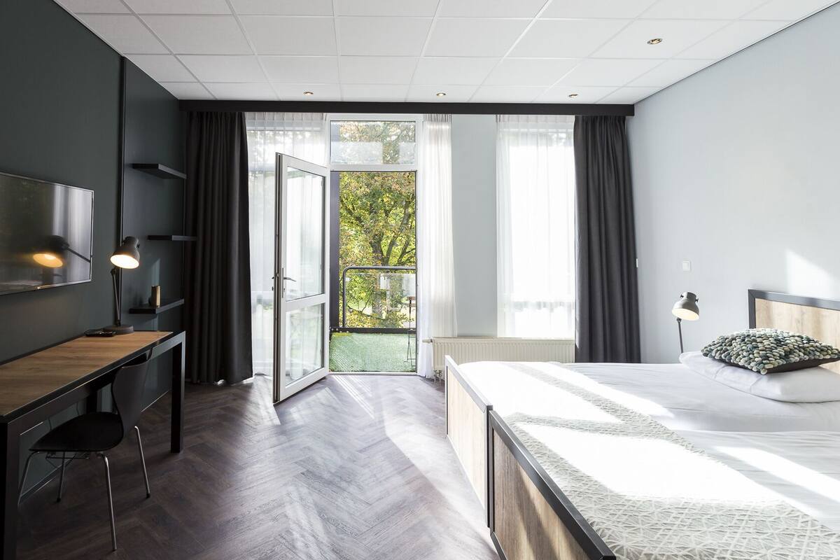 Una camera da letto moderna con un letto, una scrivania, una sedia e una televisione.