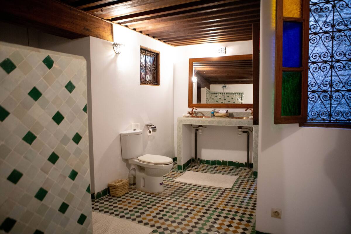 Casa de banho com sanita, lavatório e azulejos estampados.
