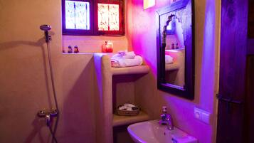 Un baño con ducha, lavamanos, espejo y una ventana con vidrieras.