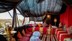 A cozy, well-decorated interior with a patterned rug, a brass lamp, and a variety of pillows and cushions. - Dar Settash (Fes)