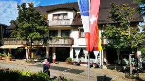 Ein zweistöckiges Gebäude mit Balkon, einer Flagge und Außenbestuhlung.