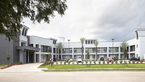 Un hotel moderno con un patio central, varios balcones y un área de estacionamiento.