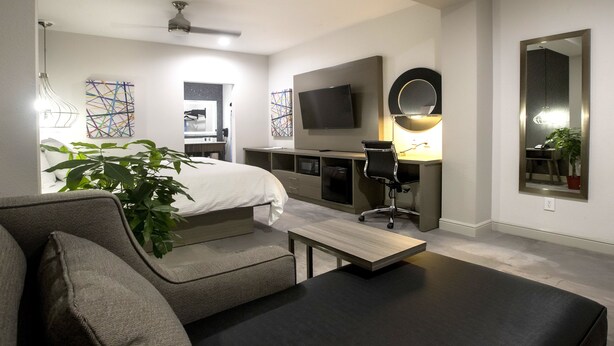 Una habitación de hotel moderna con cama, escritorio, silla, televisión y obras de arte en las paredes.