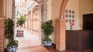 A traditional entrance with a wrought iron gate, potted plants, and a wall decorated with ceramic plates. - Hotel Rincón Poblano (Puebla)
