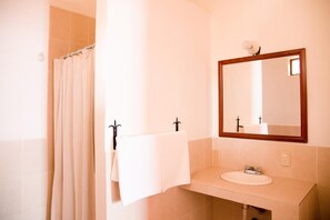 Un baño con cortina de ducha, un lavabo con espejo y una toalla colgada en la pared.