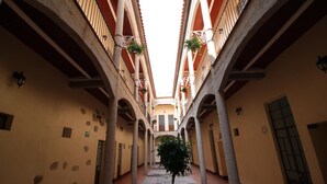 A narrow corridor with arches, a central tree, and a tiled floor. - Hotel Rincón Poblano (Puebla)