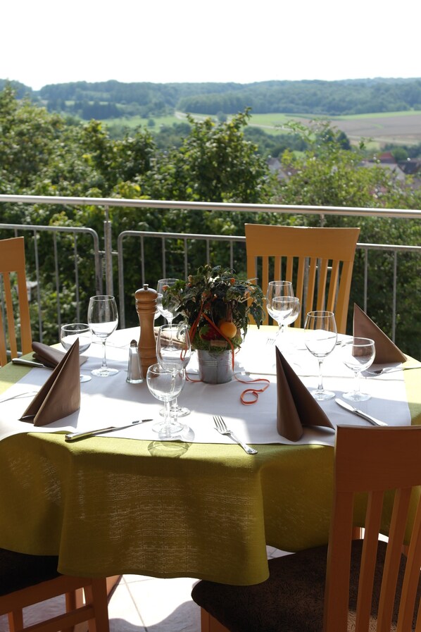 A table set for dining with a view of the countryside.