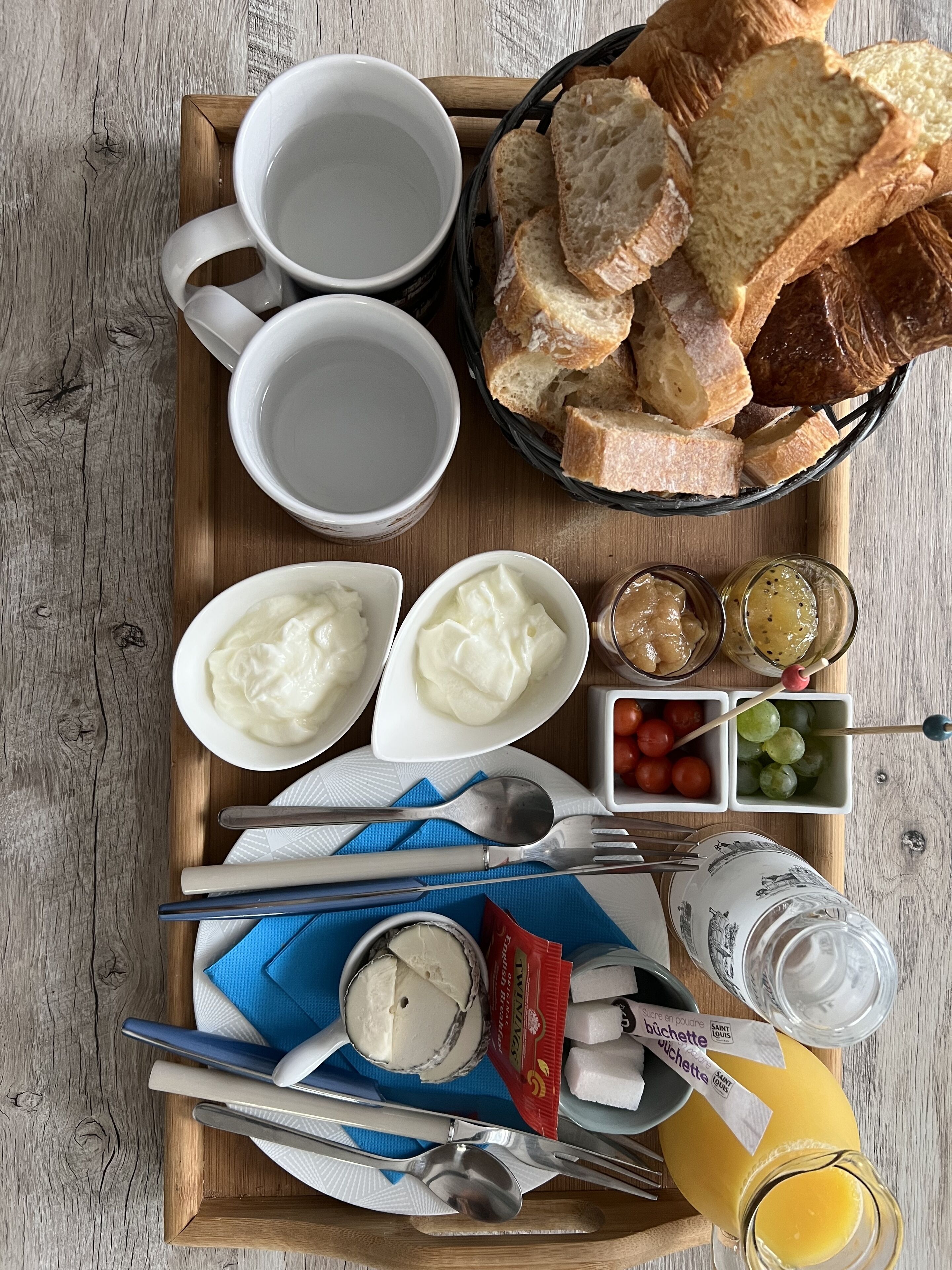 Ett frukostbricka med bröd, yoghurt, ost och juice.