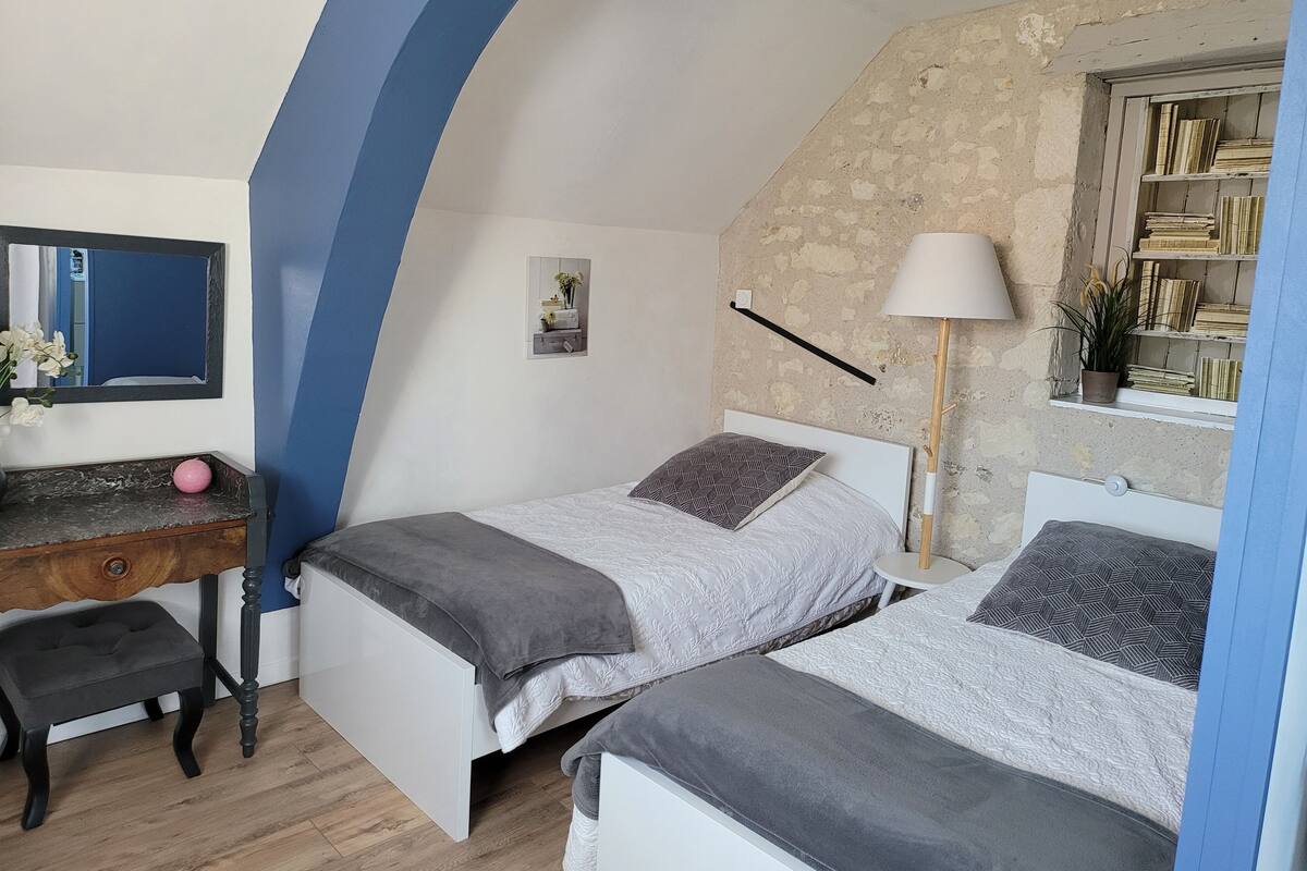 A bedroom with two beds, a desk, a chair, a lamp, and a bookshelf.