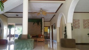 A spacious lobby with a high ceiling, a ceiling fan, and a seating area with a sofa and ottoman. - Mountain Top Villa (Mandeville)