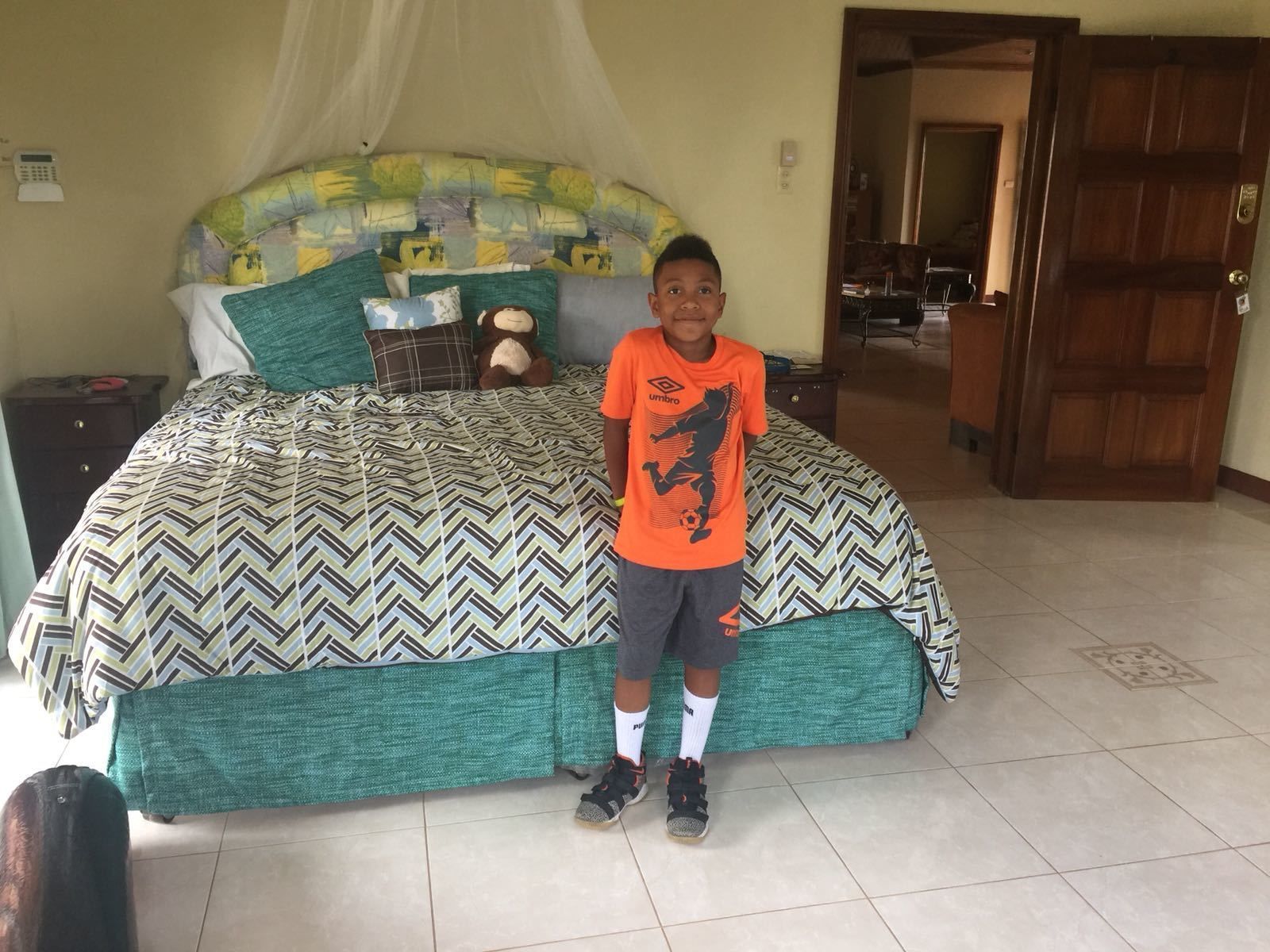 A bedroom with a bed, a nightstand, a telephone, and a door.