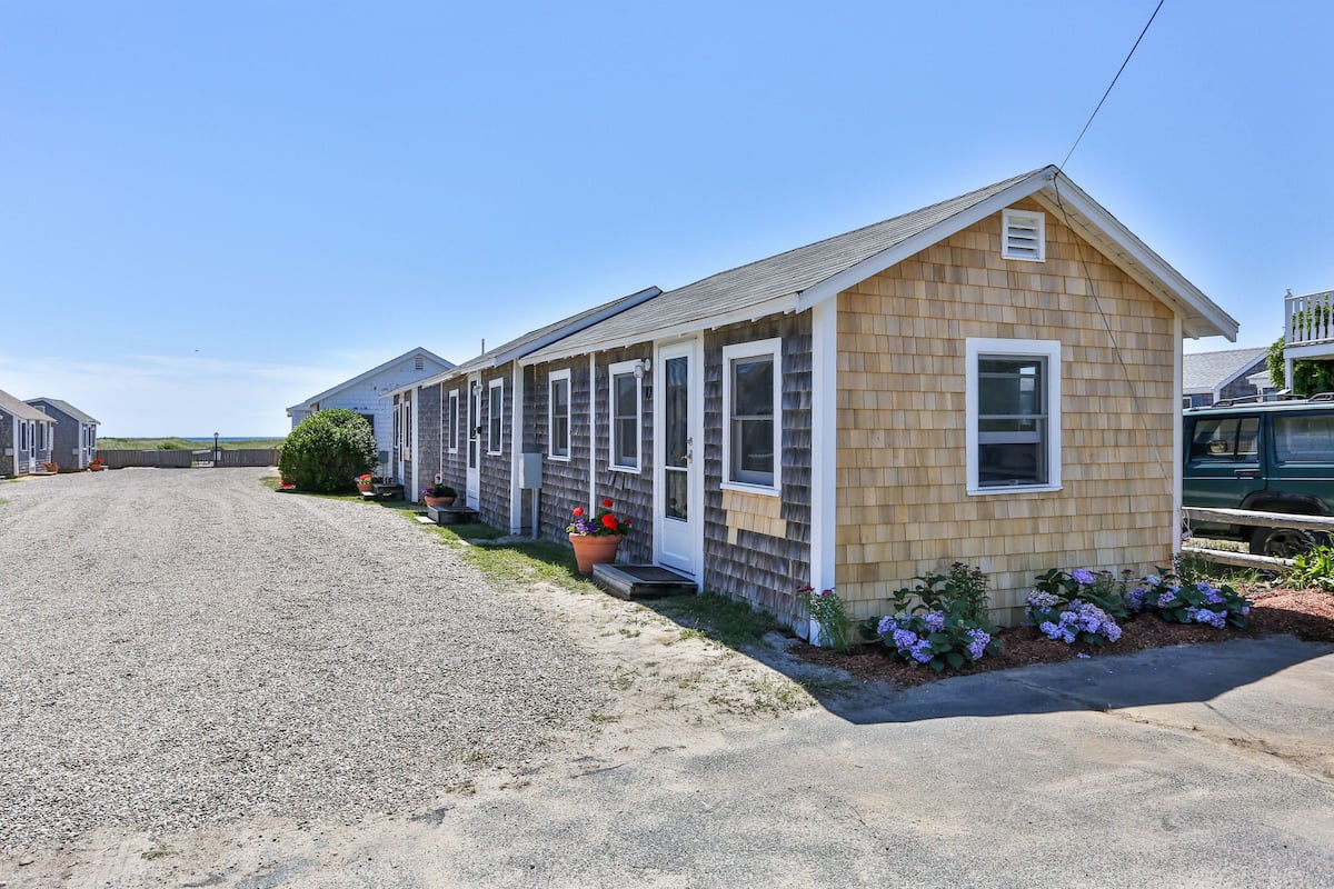 A row of mobile homes with a gravel driveway and a small garden area with flowers.