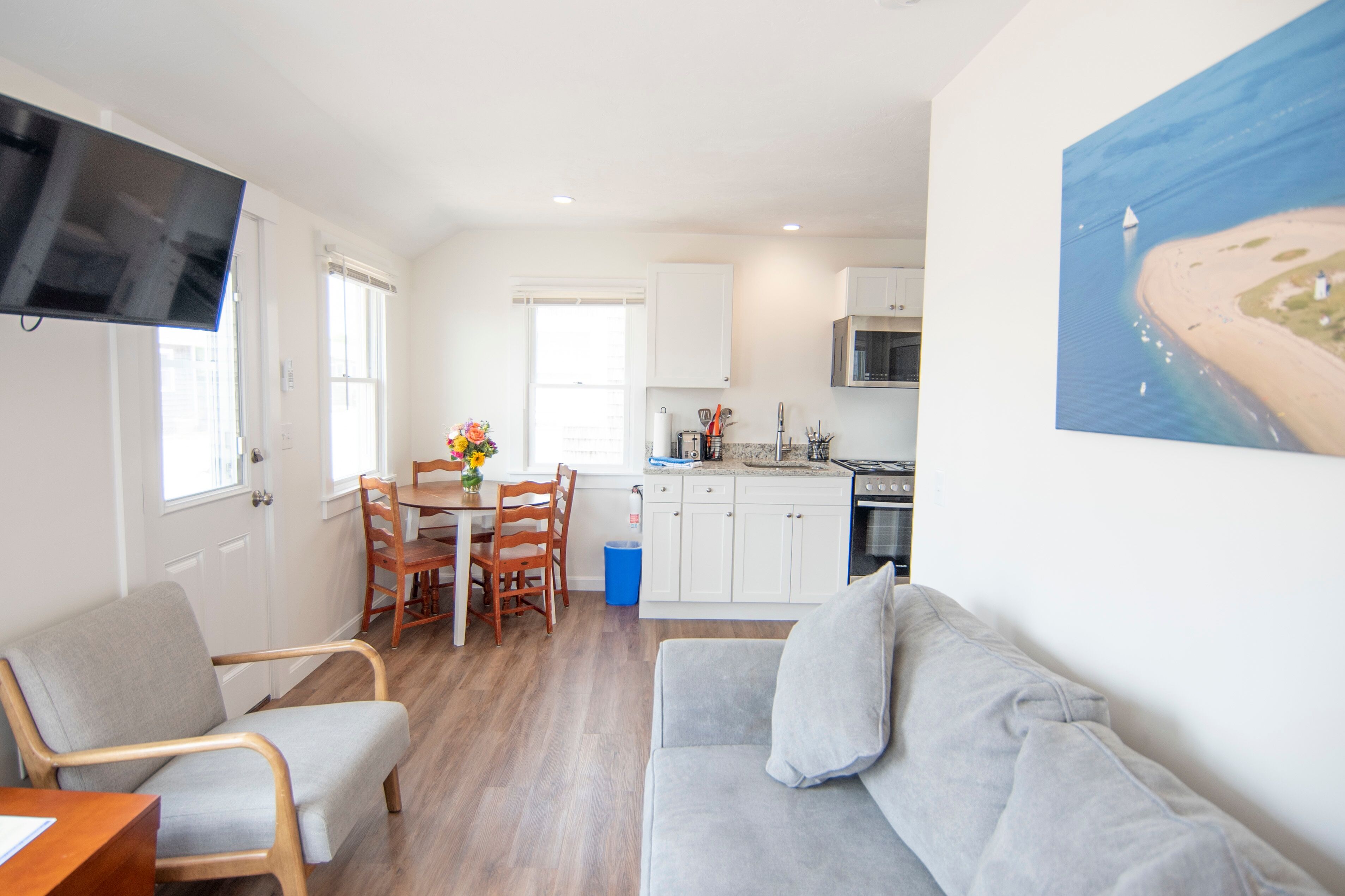 A compact living space with a kitchenette, a dining area, and a seating area with a sofa and chairs.