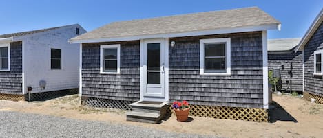 A small, single-story mobile home with a front door, two windows, and a small porch with steps.