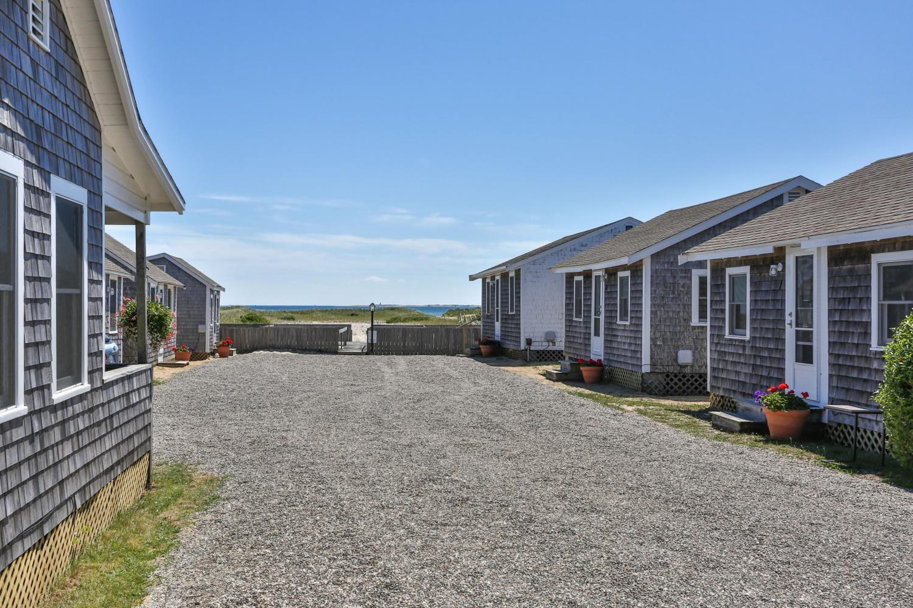 A row of mobile homes with a gravel driveway and a wooden fence in the background.