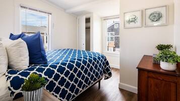 A bedroom with a bed, a potted plant, a wooden cabinet, and framed artwork on the wall.